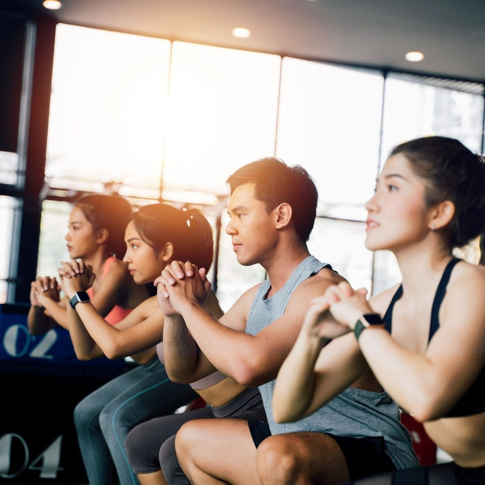 Three woman and one man in a gym doing HIIT training