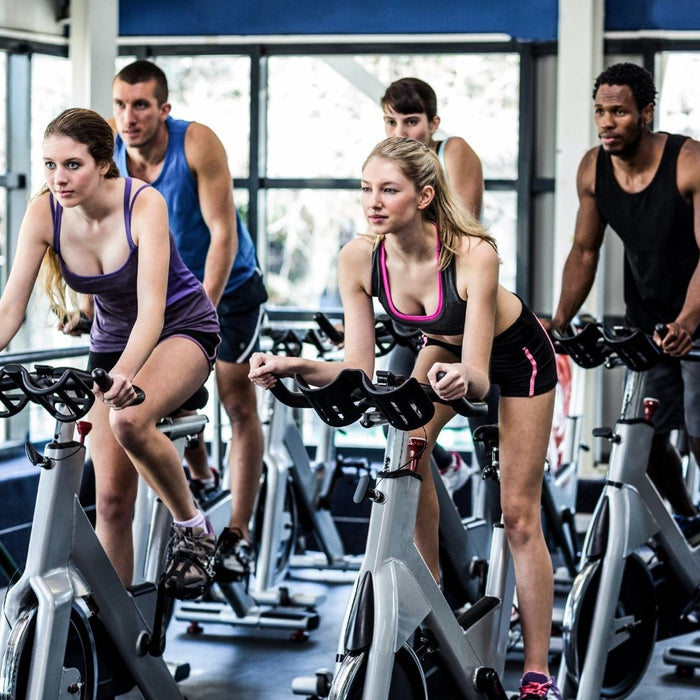 a group of men and woman doing a spin class in a gym
