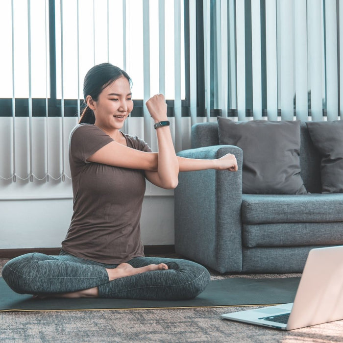 an asian woman exercising at home with laptop